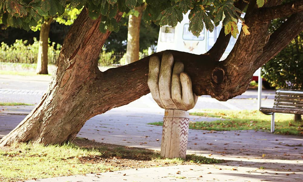 Hand sculpture holding up tree
